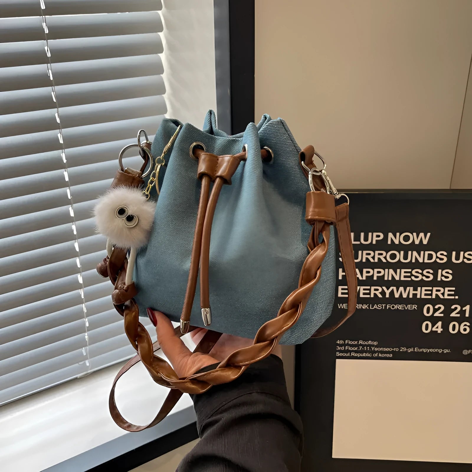 Blue one-shoulder cross body bucket bag with synthetic leather lining and hanging drop ornaments