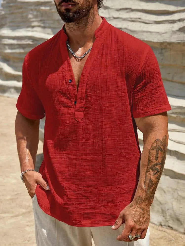 Man wearing a solid colour short-sleeve shirt with a stand collar in a casual setting.