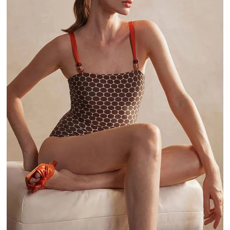 Women's printed dot pattern one-piece swimsuit with matching wrap skirt on a hanger.