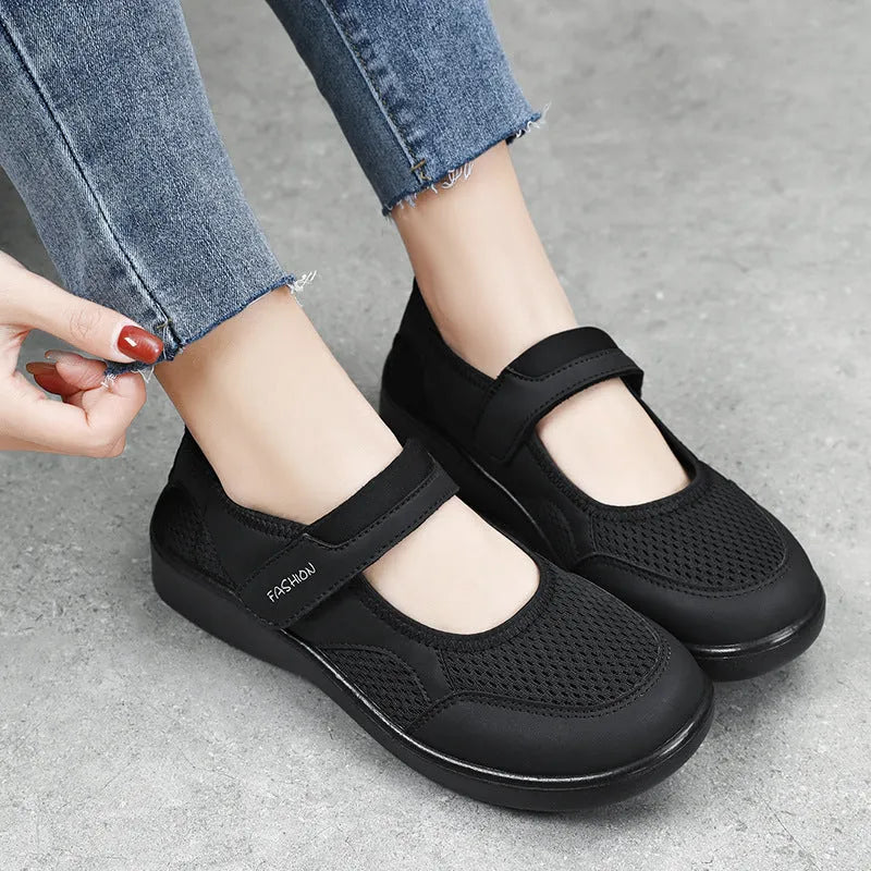 Women's grey mesh slip-on casual shoes with Velcro strap fastening on a flat sole.