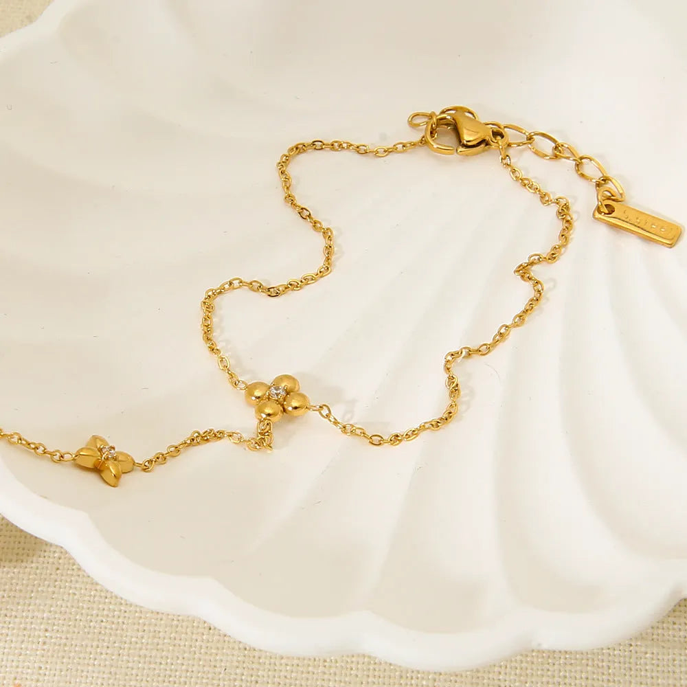Gold stainless steel women's bracelet with floral and eight-pointed star geometric design.