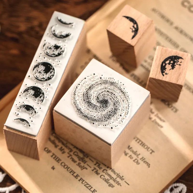 Set of seven wooden craft stamps for DIY journal decoration in stars and moon or plant catalog designs.