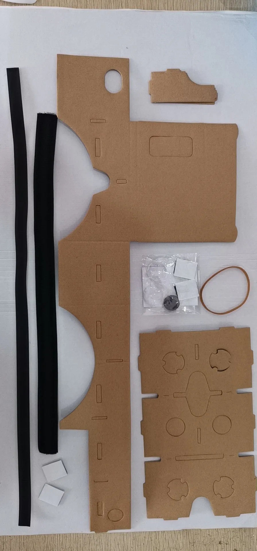 Pink and white folding cardboard VR glasses viewer for smartphones with 3D lenses and head strap.