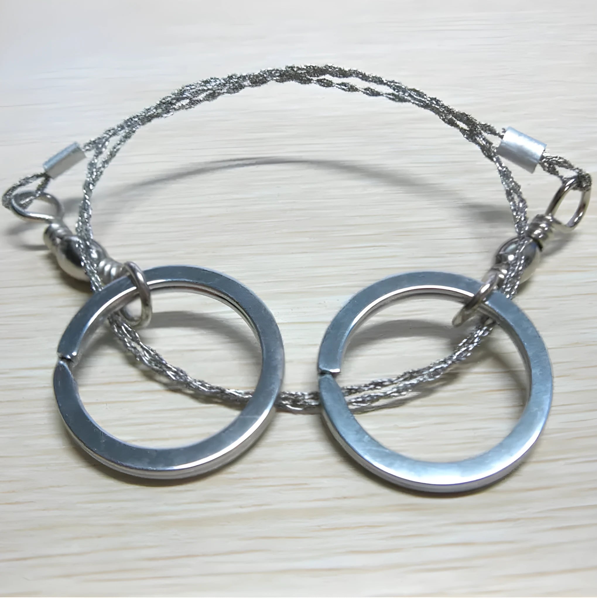 Stainless steel survival wire saw with thumb rings, total length 70cm for outdoor cutting tasks.