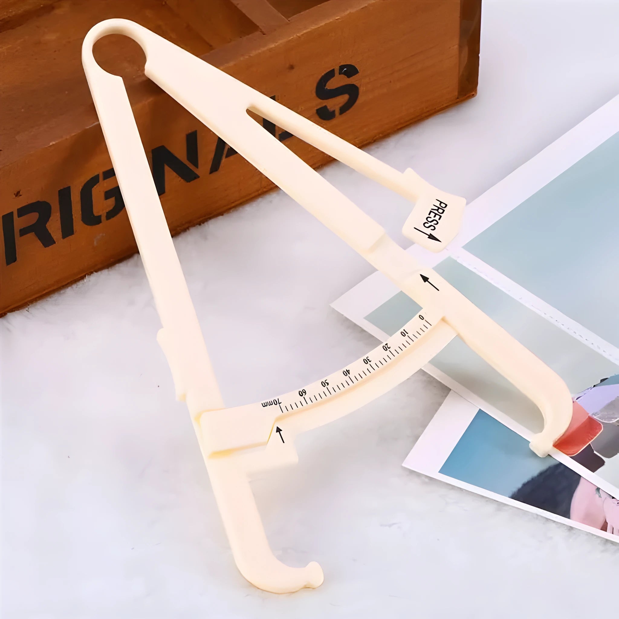 Clear acrylic body fat caliper showing measurement scales for skin fold thickness assessment