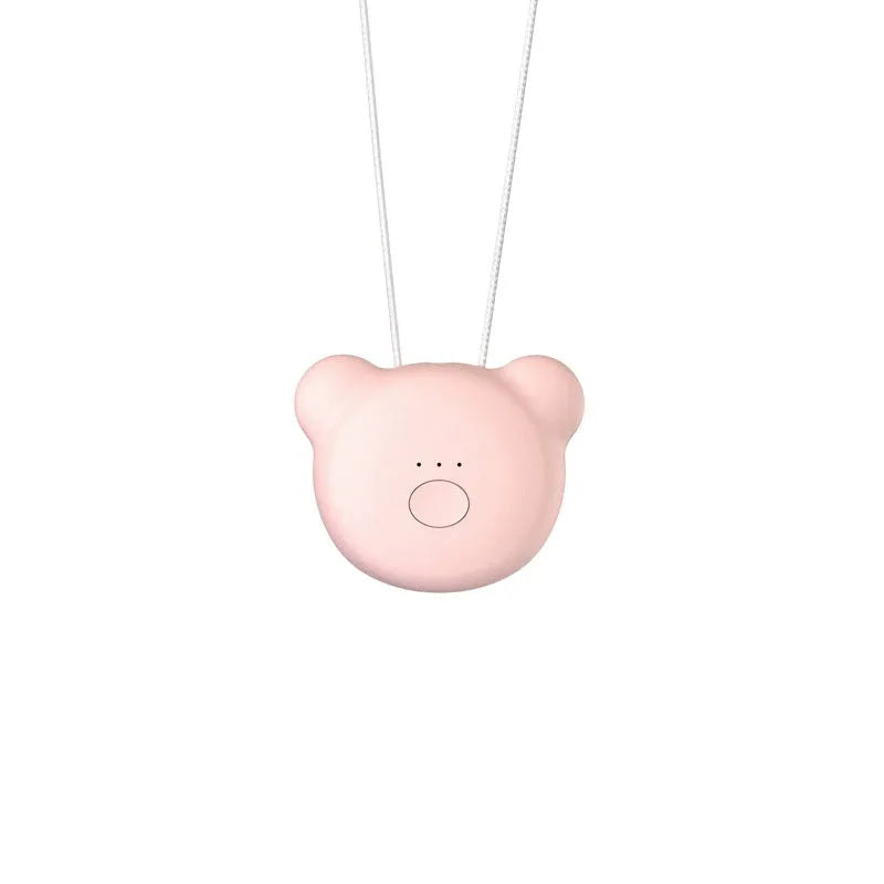 Small pink USB portable air purifier necklace on a table with charging cable.