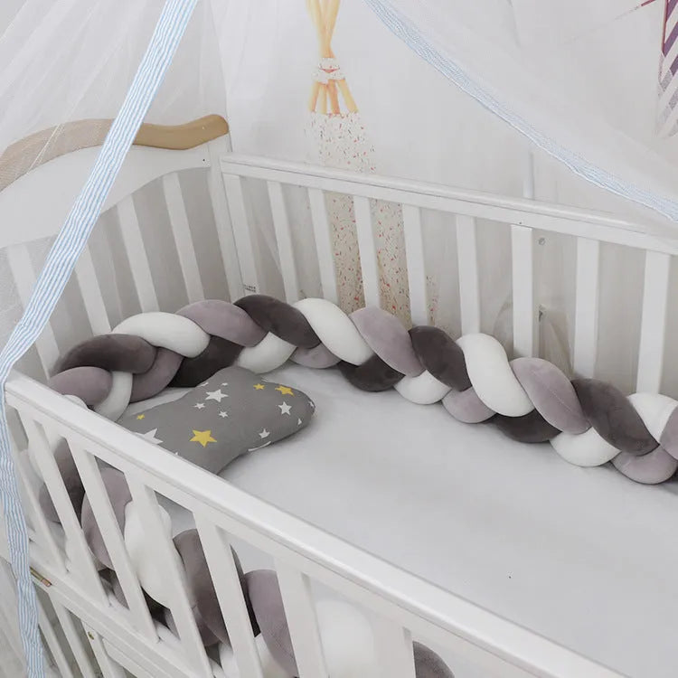 Bendable braid-knot baby crib bumper in spandex velvet, shown in a light grey colour wrapped around a cot.