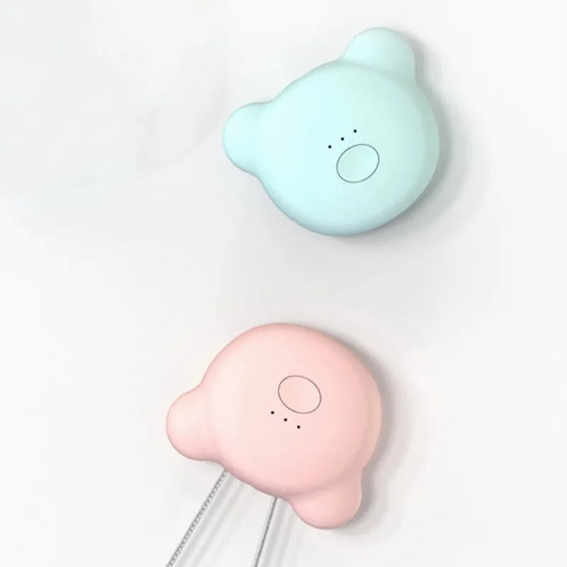 Small pink USB portable air purifier necklace on a table with charging cable.