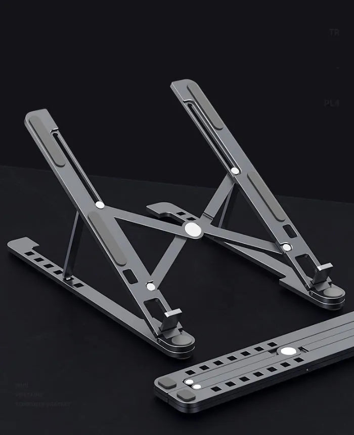Silver foldable aluminium laptop stand holding a MacBook at an angle, shown next to a backpack.
