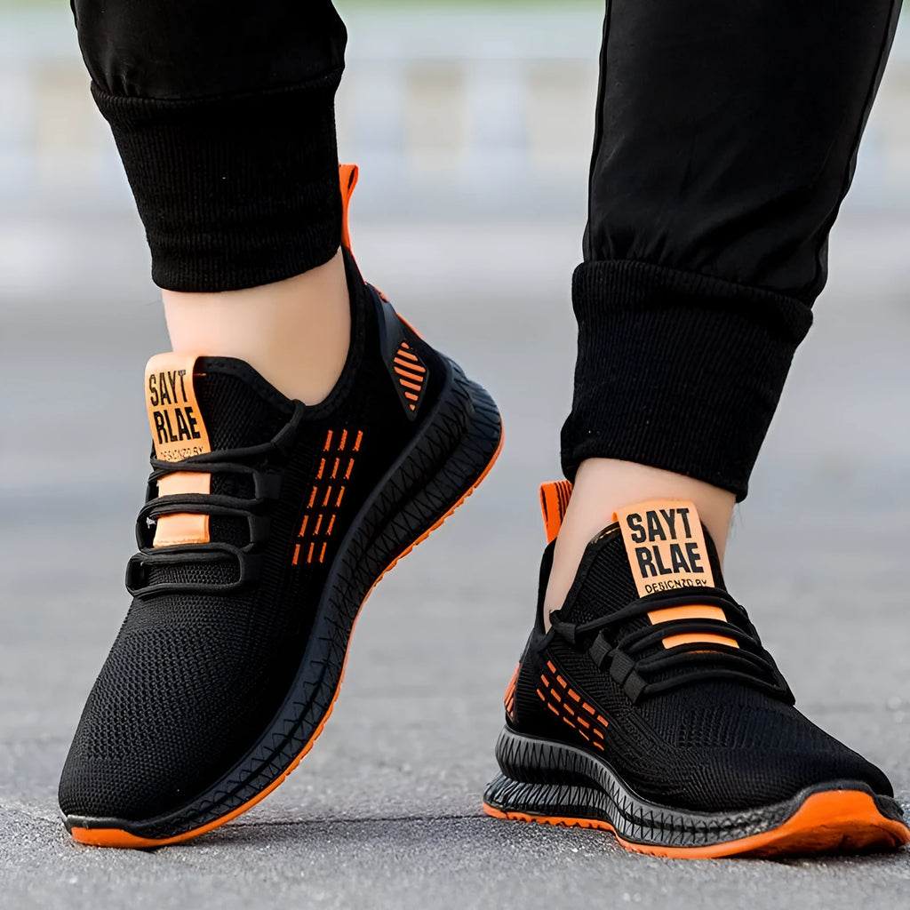 Men's low-top casual sports shoes with Flying Weave upper, cross straps on striped pattern, and flat sole.
