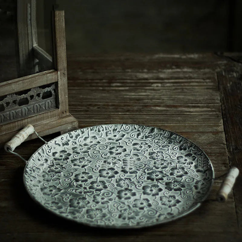 Round wrought iron storage tray in a classic metal colour on a wooden surface.
