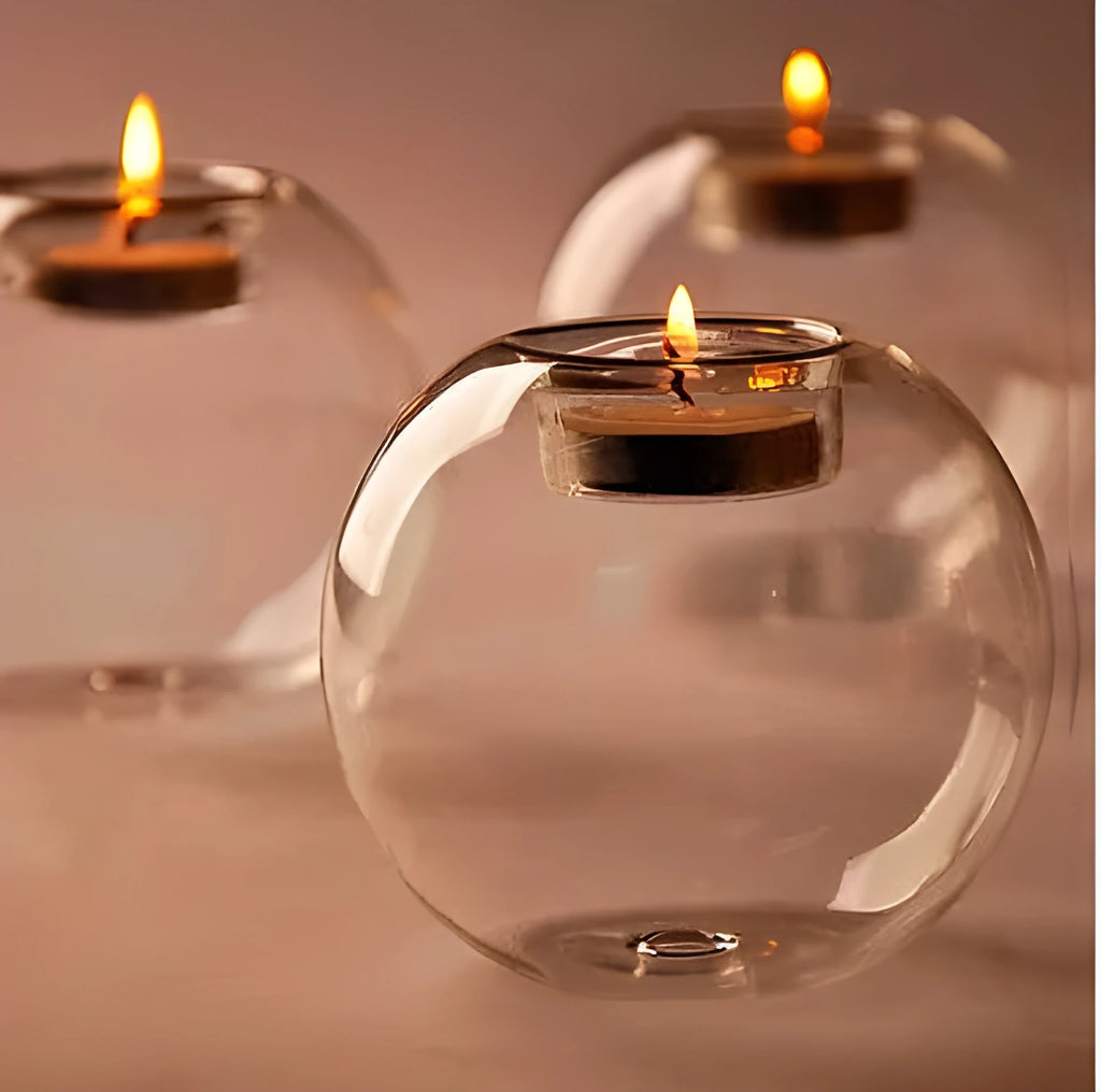 Handmade round hollow glass candle holder with openwork holes, shown on a table.