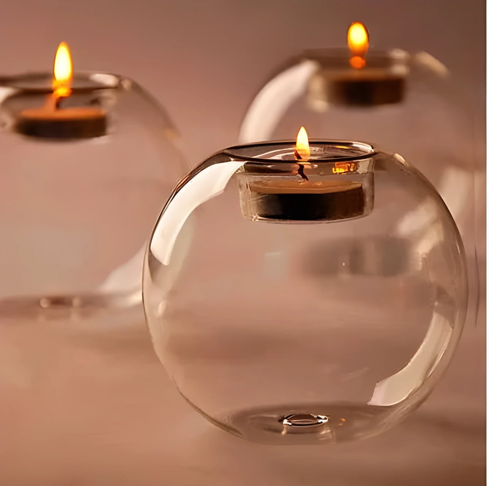 Handmade round hollow glass candle holder with openwork holes, shown on a table.