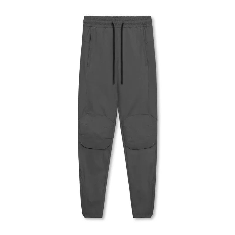 Men's loose grey fitness trousers with ankle ties on a gym floor.