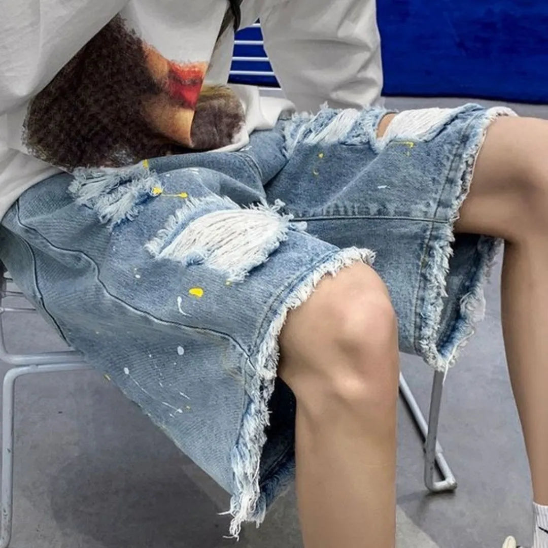 Men's loose fit water washed denim shorts with hole details in light blue, showing fifth pants length.