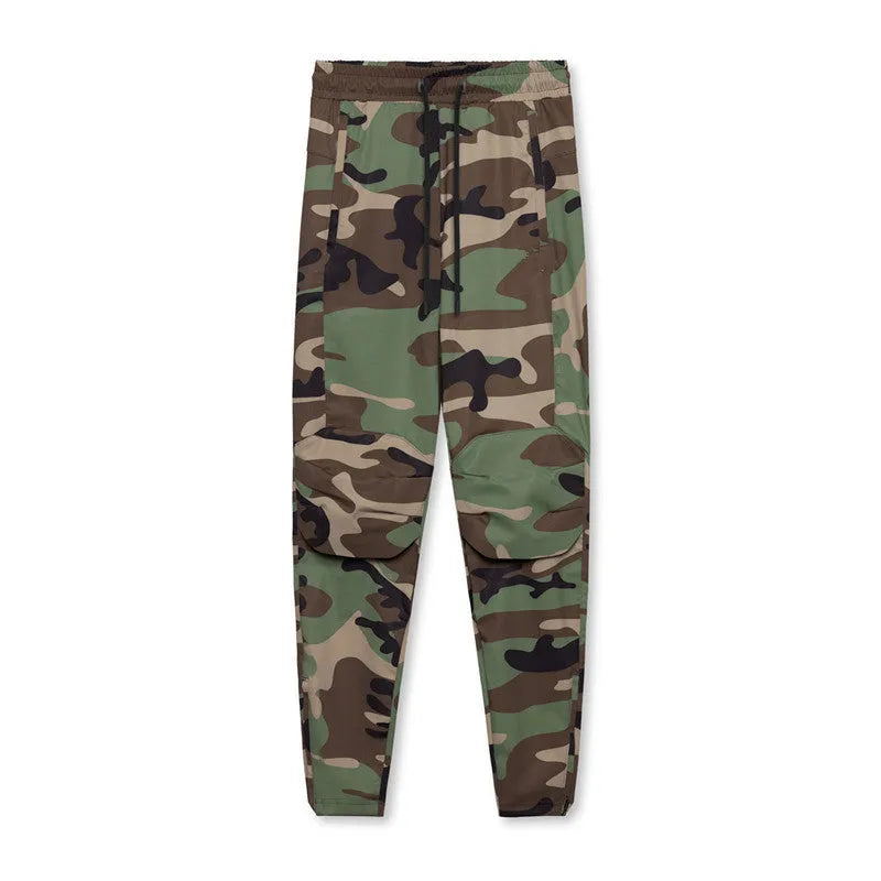 Men's loose grey fitness trousers with ankle ties on a gym floor.