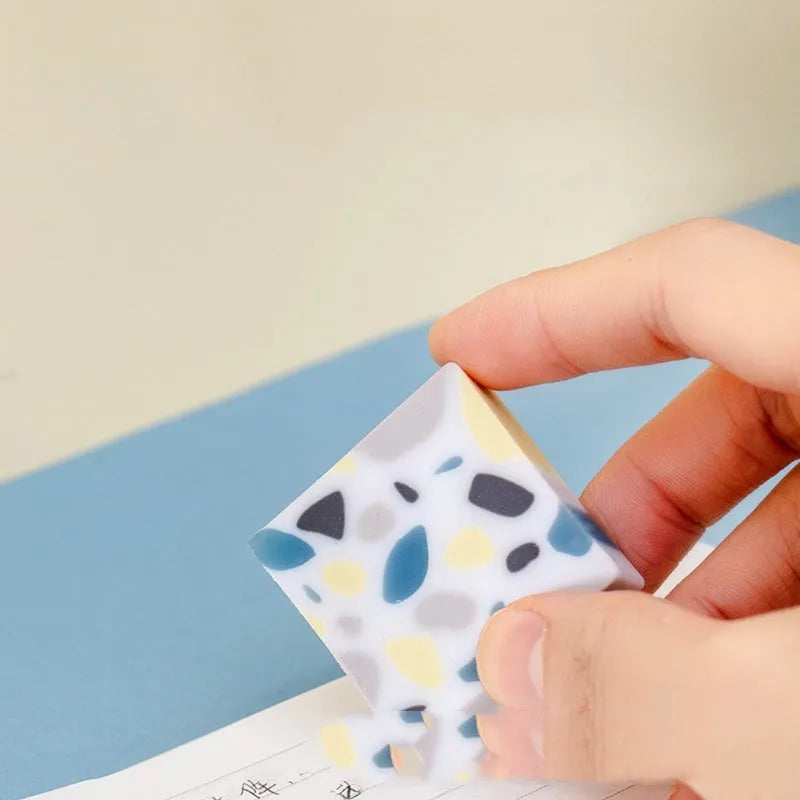 White brick-shaped rubber eraser on a surface, a stationery tool for pencil mark removal.