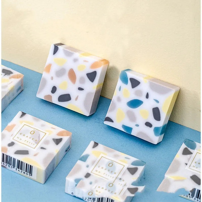 White brick-shaped rubber eraser on a surface, a stationery tool for pencil mark removal.