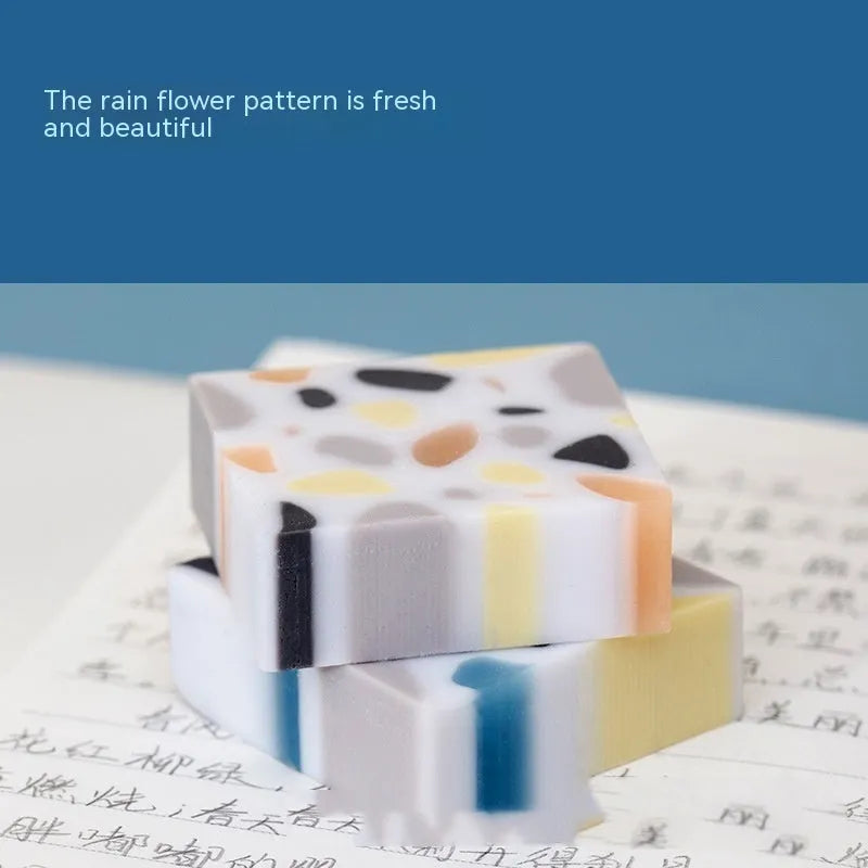 White brick-shaped rubber eraser on a surface, a stationery tool for pencil mark removal.