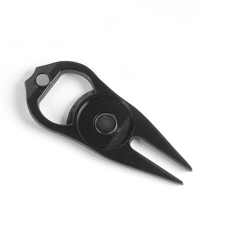 Black zinc alloy golf ball fork and bottle opener tool on green turf