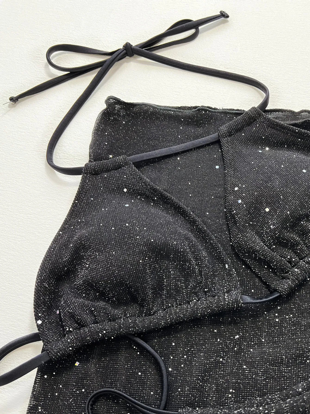 Black three-piece bikini swimsuit set showing separate top and shorts on mannequin