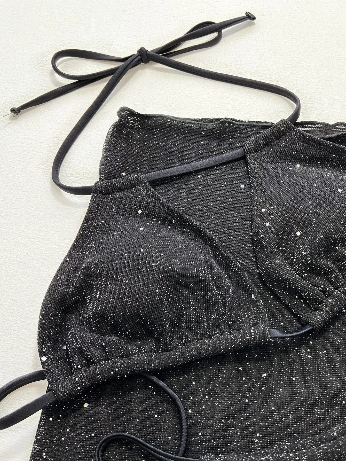 Black three-piece bikini swimsuit set showing separate top and shorts on mannequin