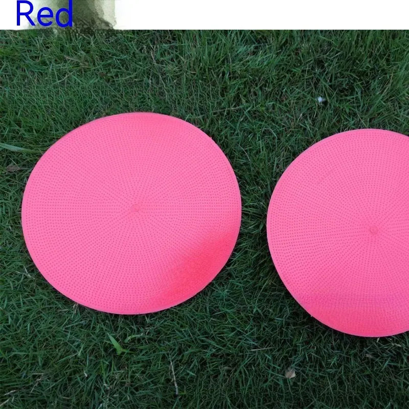 Flat, round yellow football training target disc with 23cm diameter on grass.