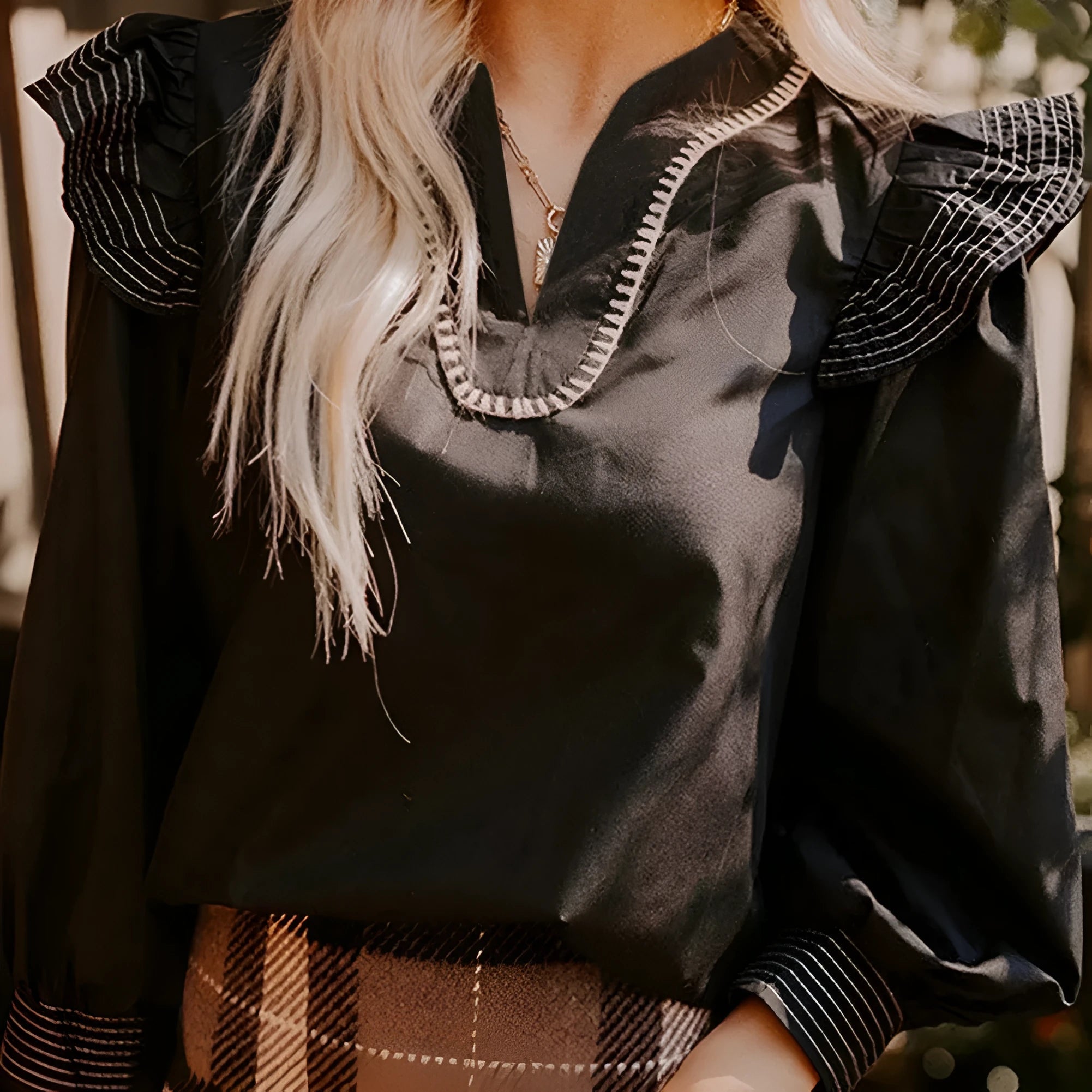 Black women's blouse with V-neck, long ruffle sleeves, and contrast stitch detail.