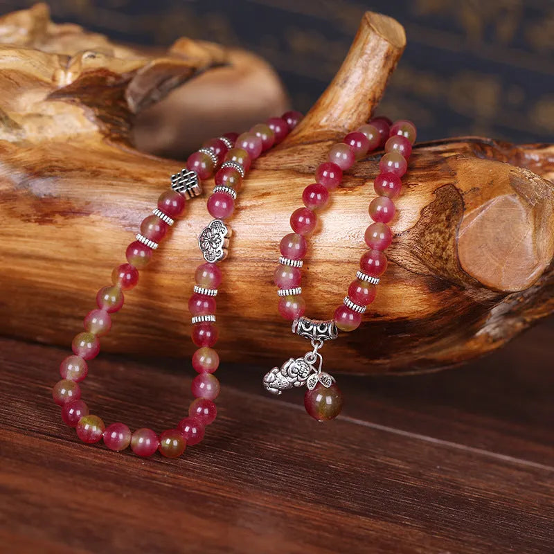 Natural watermelon crystal bracelet with a handmade Chinese knot closure, showing geometric beads.