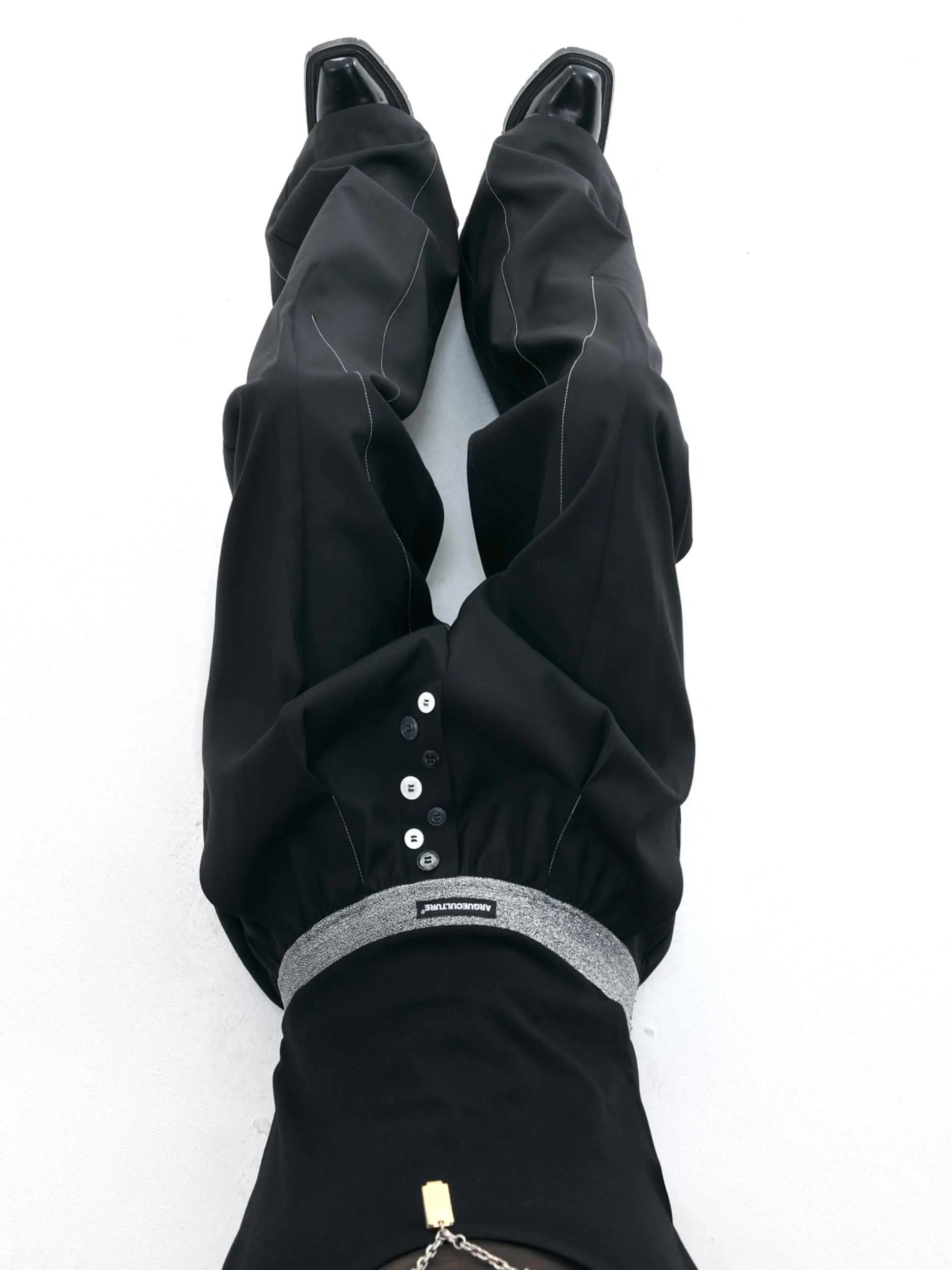Men's grey straight-leg high-waisted trousers with a button-fly opening on a neutral background.
