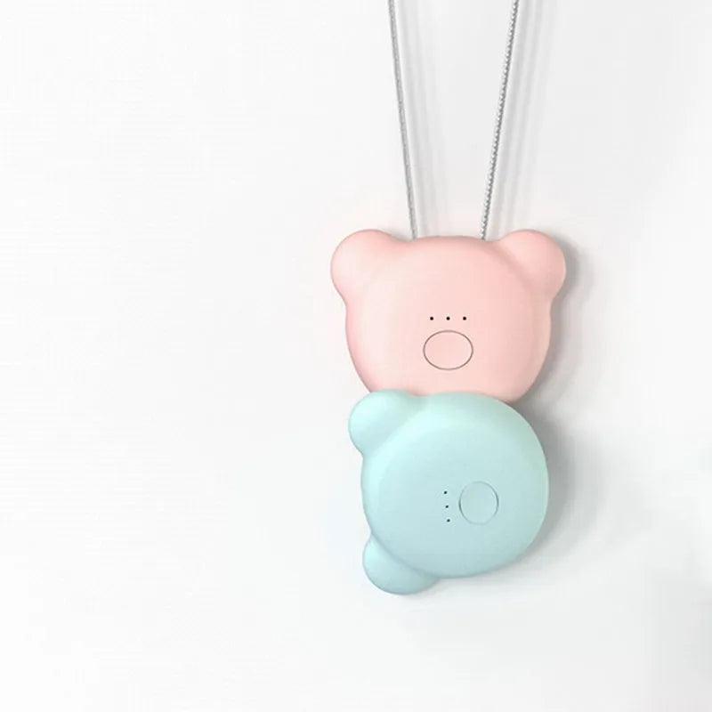 Small pink USB portable air purifier necklace on a table with charging cable.