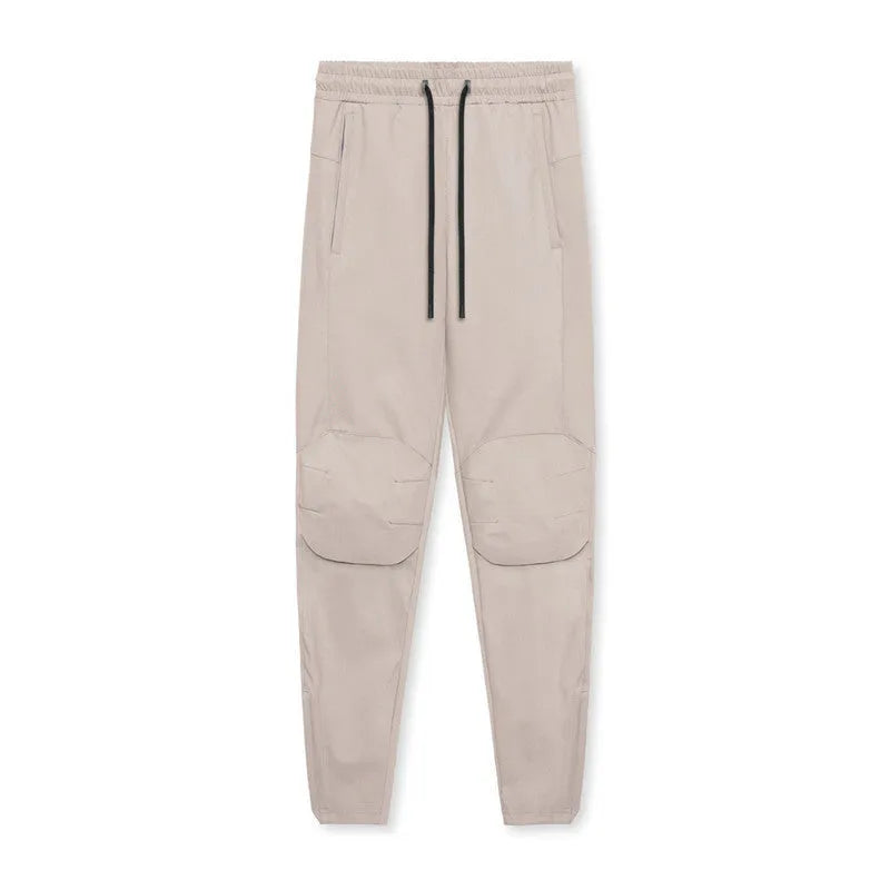 Men's loose grey fitness trousers with ankle ties on a gym floor.