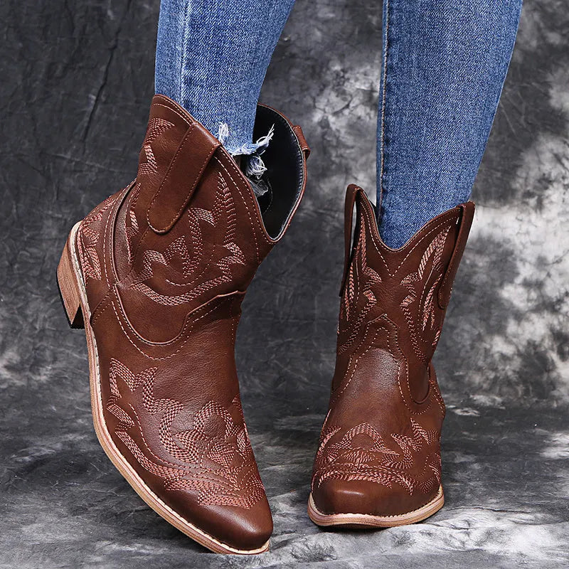 Women's blue embroidered cowboy boots with low wedge heel and pointed toe on a white background.