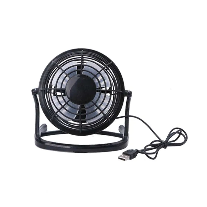Black mini USB desk fan with adjustable head on a wooden desk next to a laptop.