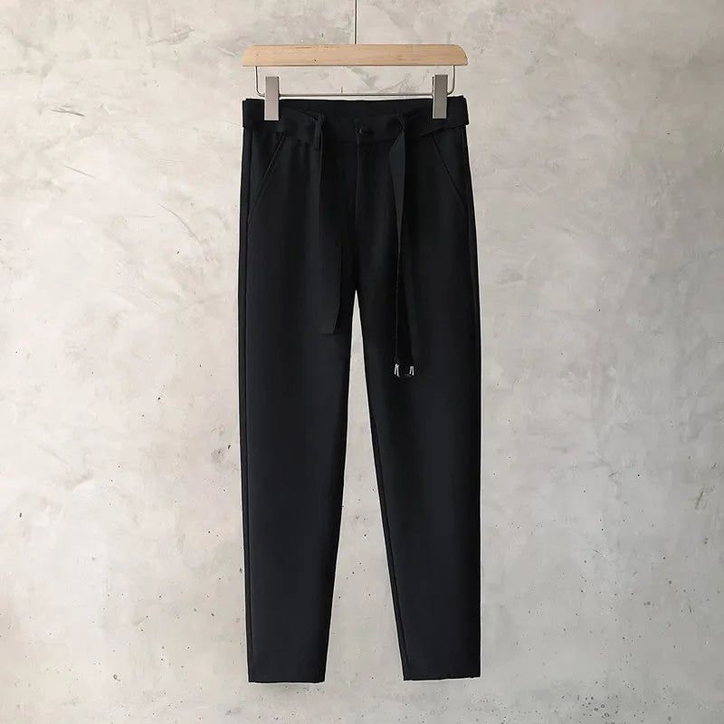Boy wearing slim straight wool trousers in a neutral colour, showcasing the tapered fit and straight leg opening.