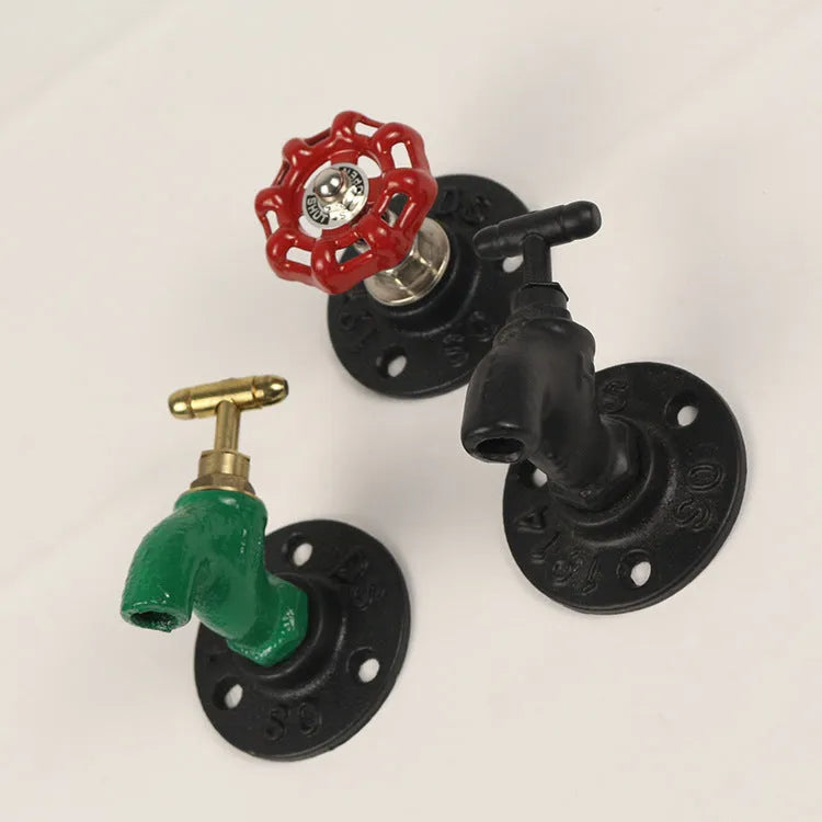 A polished metal wall hook in a water pipe design, shown in black, green, and red colour options.