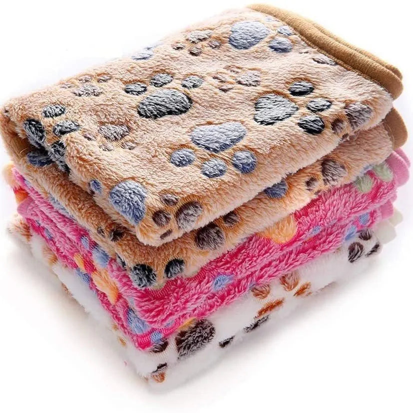 Coral fleece pet blanket with dog's paw print pattern in beige, shown in a large size on a dog bed.