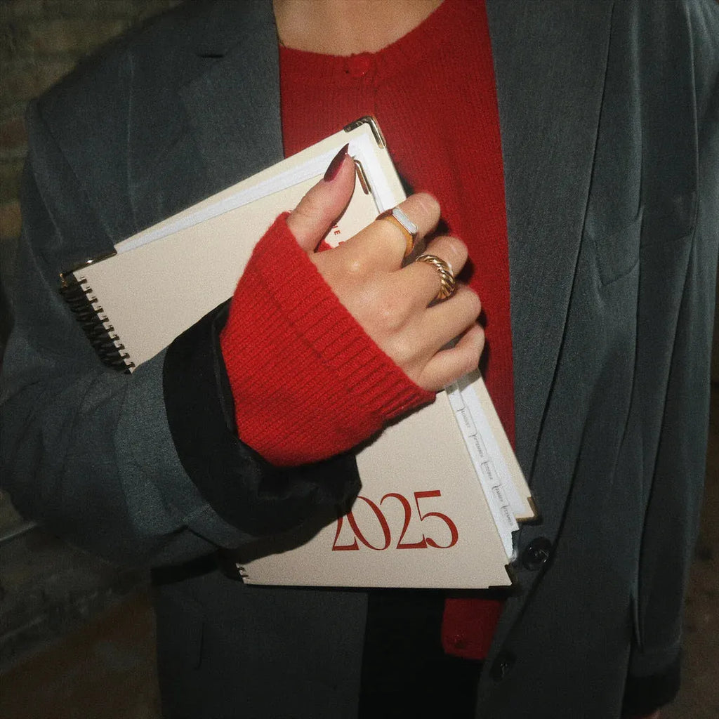 Cherry Red coil notebook open to show daily schedule pages and wire-bound spine