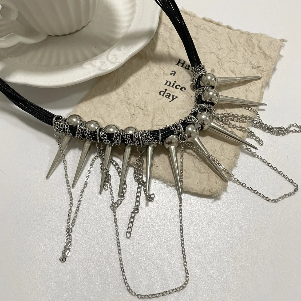 Women's leather necklace with electroplated finish showing rivet decoration and winding tassel design with round beads