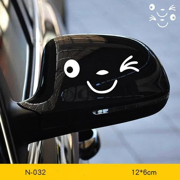 A pair of reflective cartoon eye car stickers on a vehicle rearview mirror.