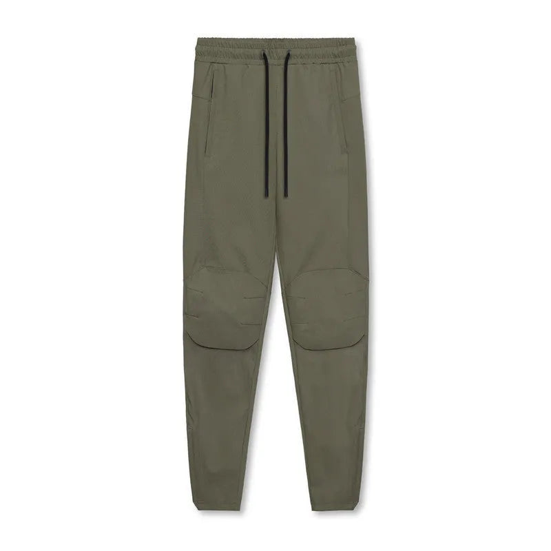 Men's loose grey fitness trousers with ankle ties on a gym floor.