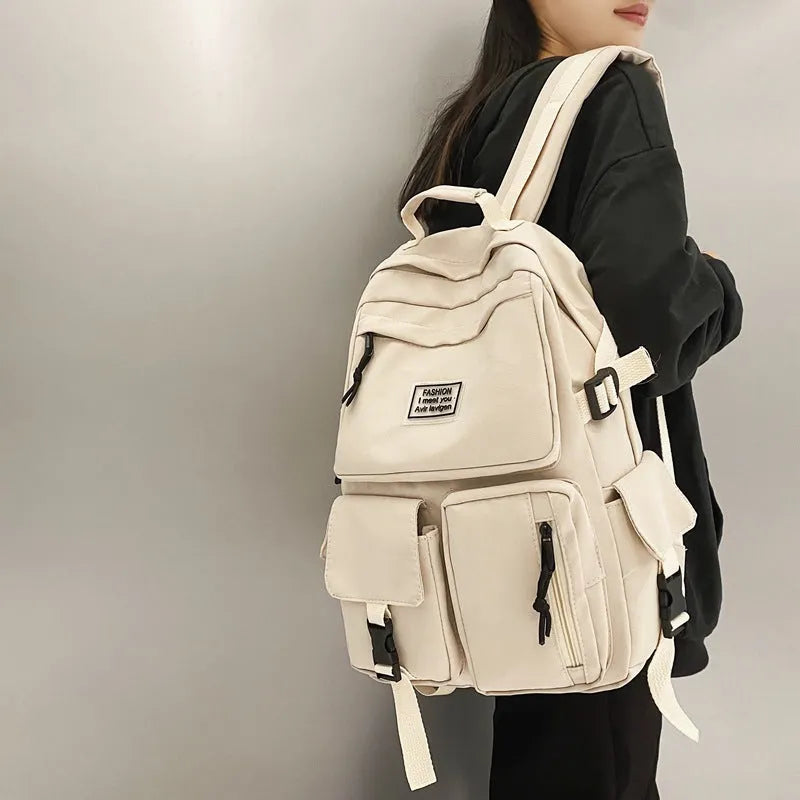 Black and white nylon student backpack with front 3D pockets, shown with laptop in compartment.