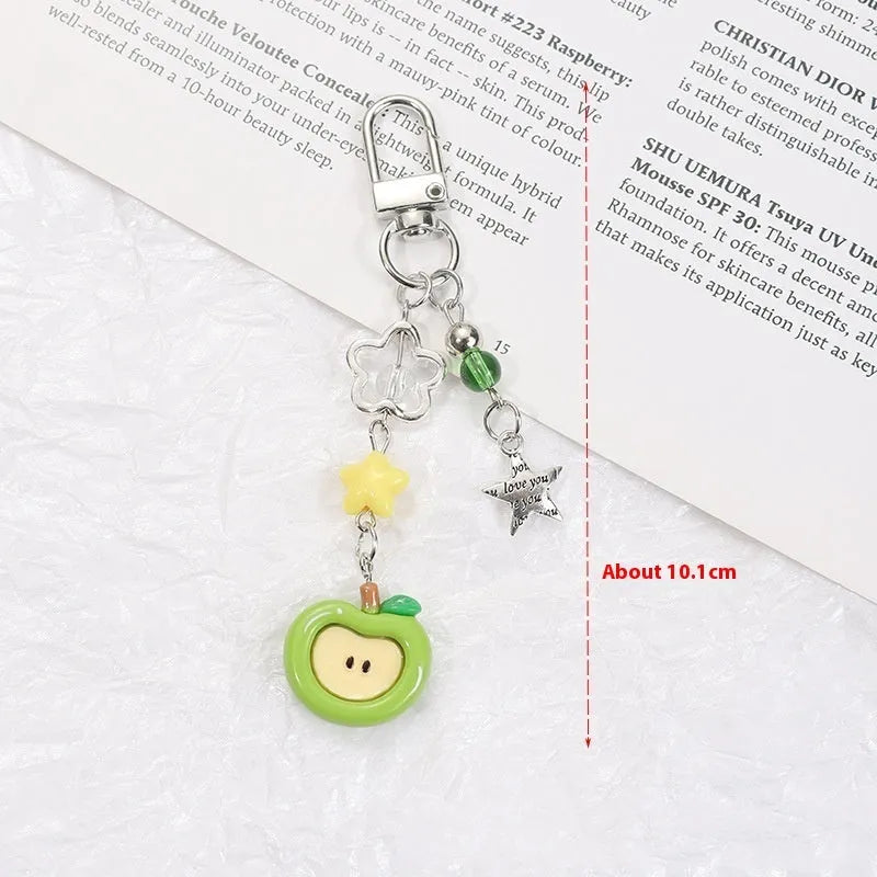 Plastic resin fruit charm keychain with removable rope in strawberry, green apple, and red apple designs.
