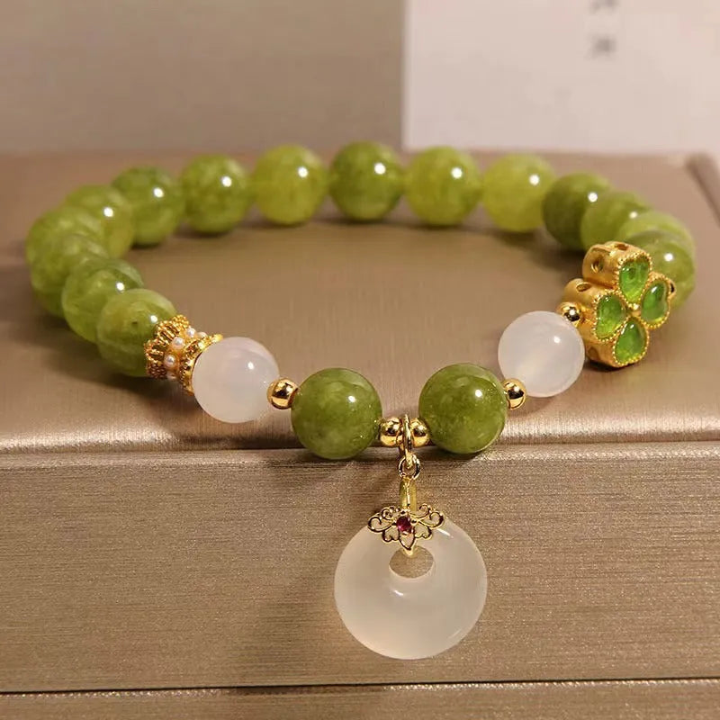 Green tourmaline four-leaf clover women's bracelet with safety buckle clasp on a white background.