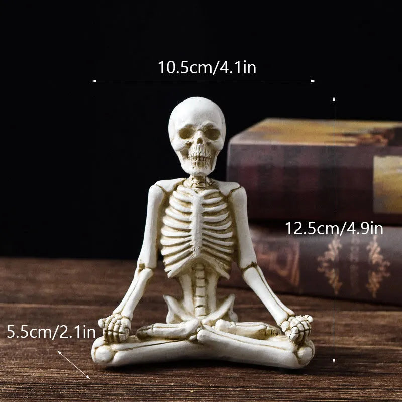 Detailed resin ornament of a yoga pose skeleton skull on a desktop, shown in black and white colour options.
