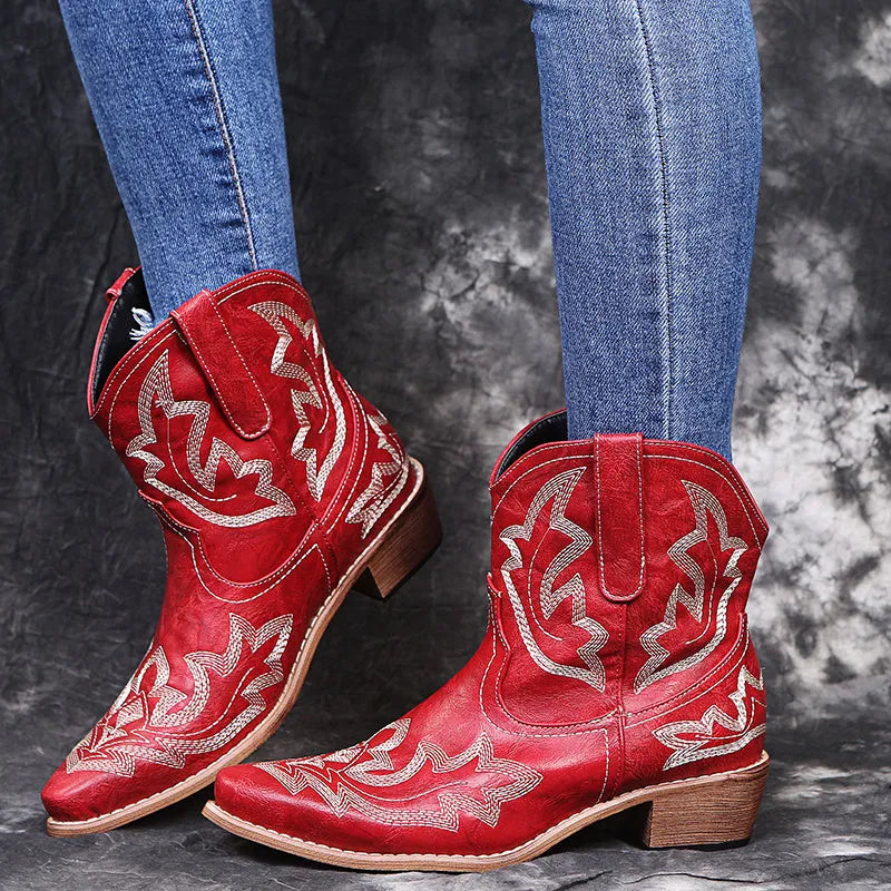 Women's blue embroidered cowboy boots with low wedge heel and pointed toe on a white background.