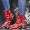 Women's blue embroidered cowboy boots with low wedge heel and pointed toe on a white background.