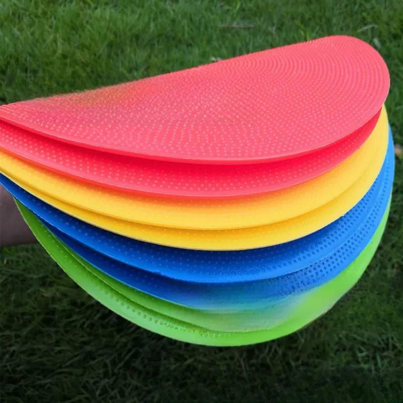 Flat, round yellow football training target disc with 23cm diameter on grass.