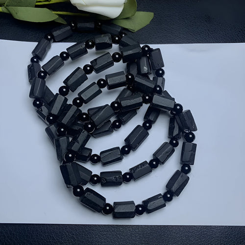 Black tourmaline rough stone bracelet with unpolished beads on a wrist.