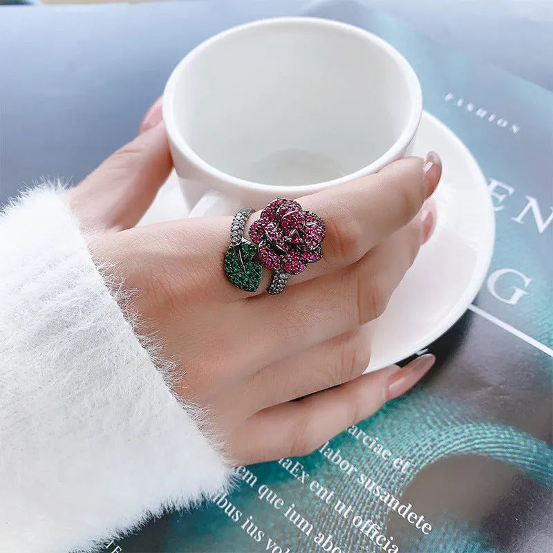 Geometric black gold flower ring with simulation red corundum centrepiece on female hand